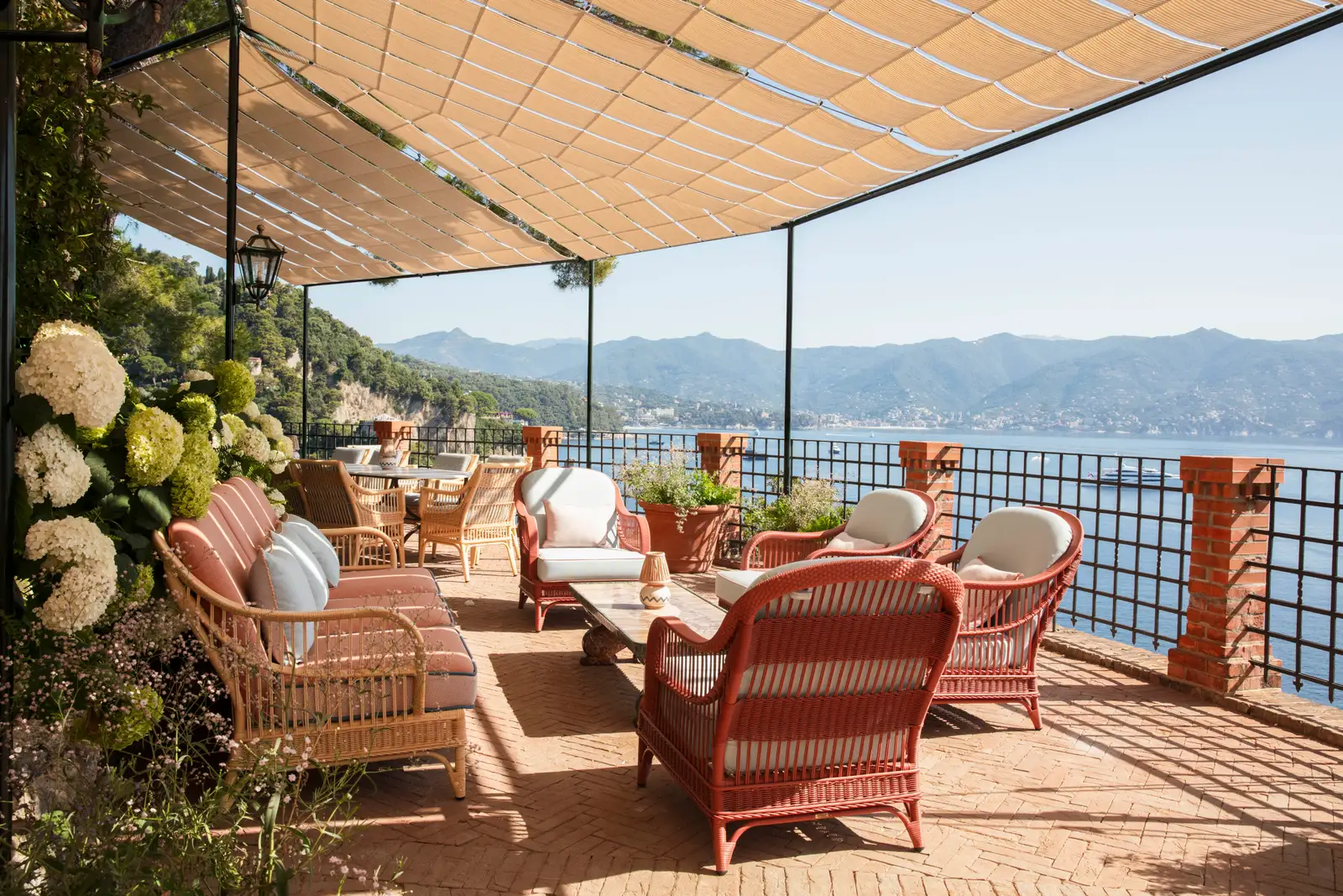 Villa Beatrice’s terrace, red wicker sofas under the pergola and the Gulf of Tigullio.