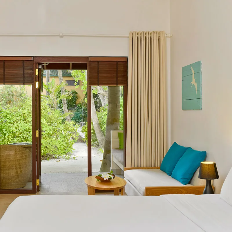 A bed, sofa and garden beyond sliding doors.