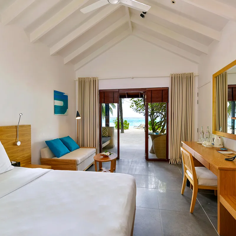The bungalow interior with a king bed and veranda towards the beach.
