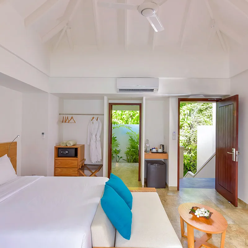 The room interior, with a sofa, open-air bathroom and a door towards the stairs.