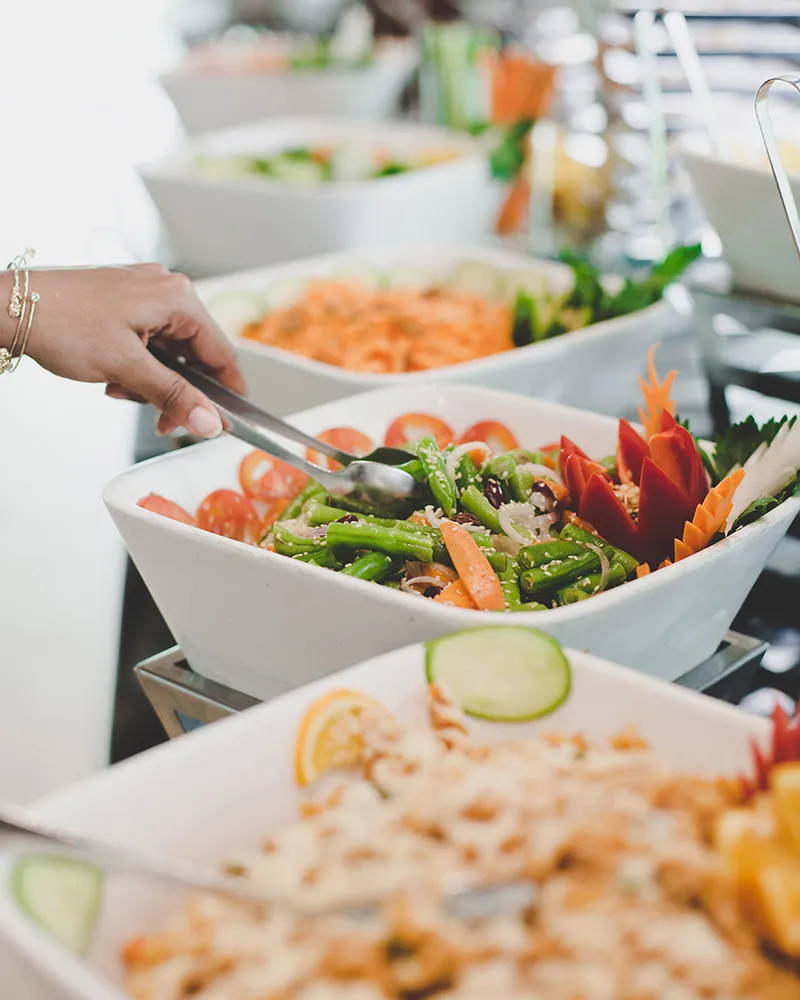 A hand serving salad at the buffet.
