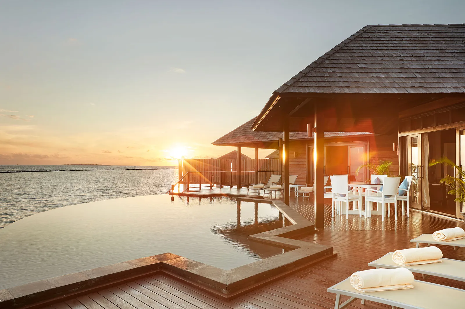 The Aqua Retreat at sunset: the infinity pool, the dining pavilion and the deck over the water.