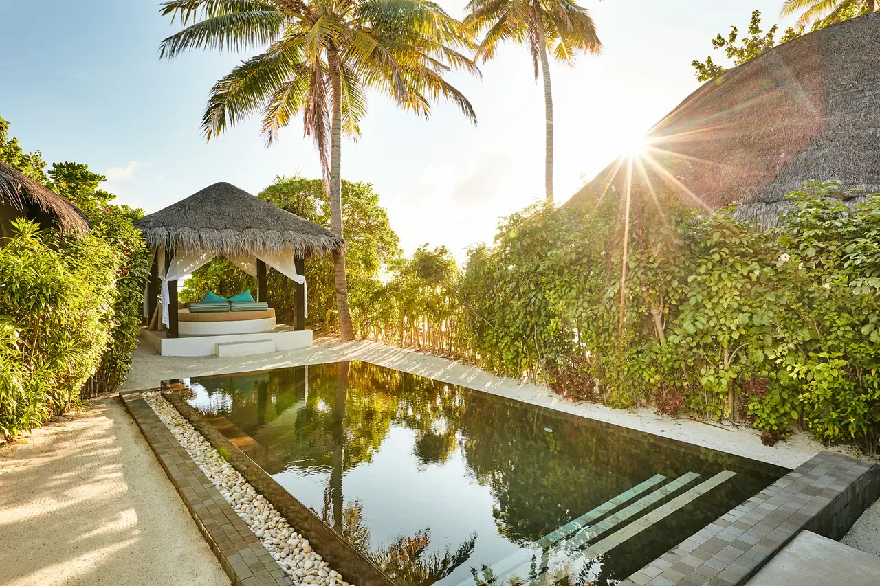 The long pool of a Deluxe Beach Villa with Pool in the afternoon sun, with its cabana and loungers.