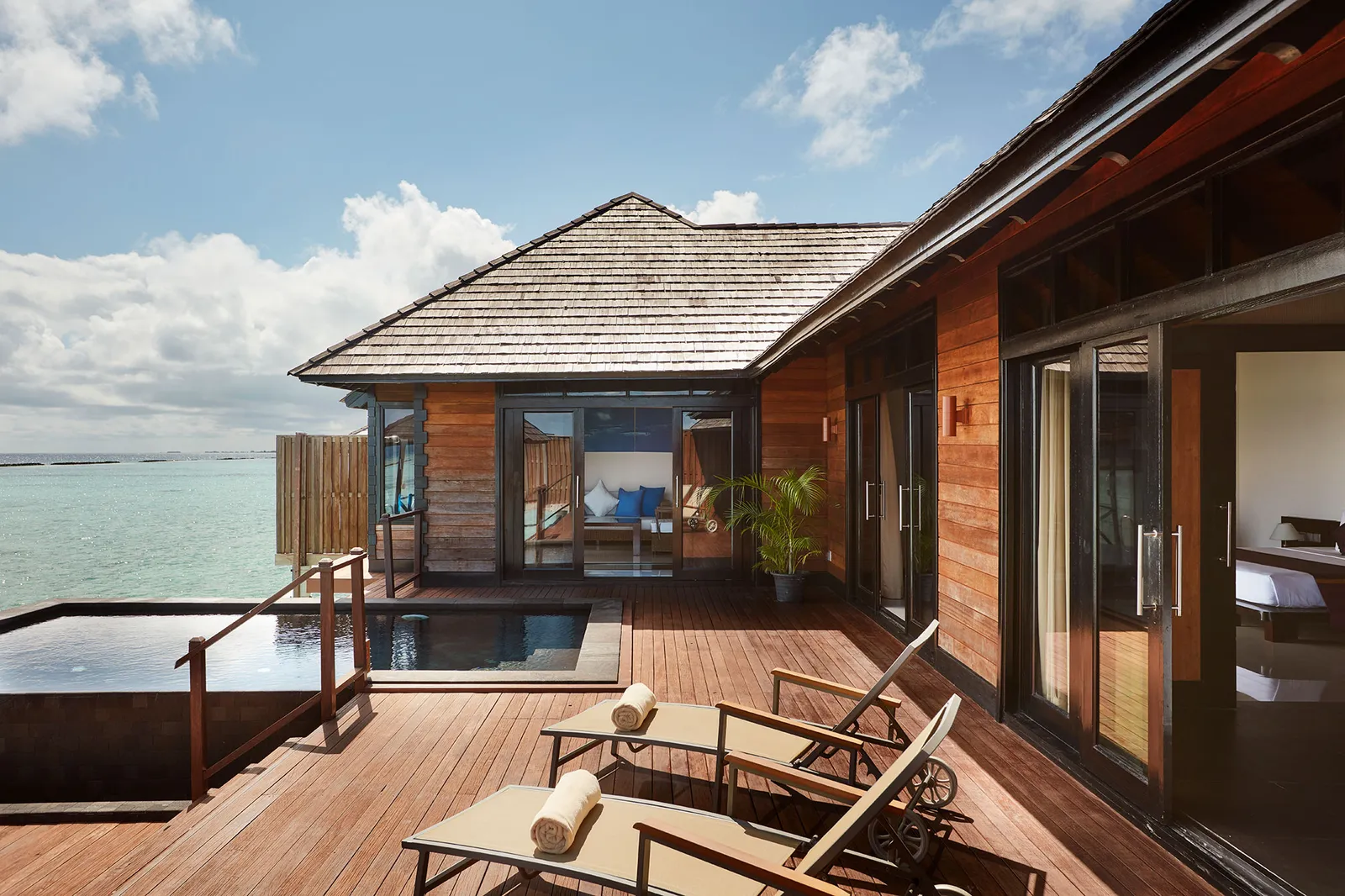 An Infinity Water Villa’s deck, with loungers and the infinity pool over the lagoon.