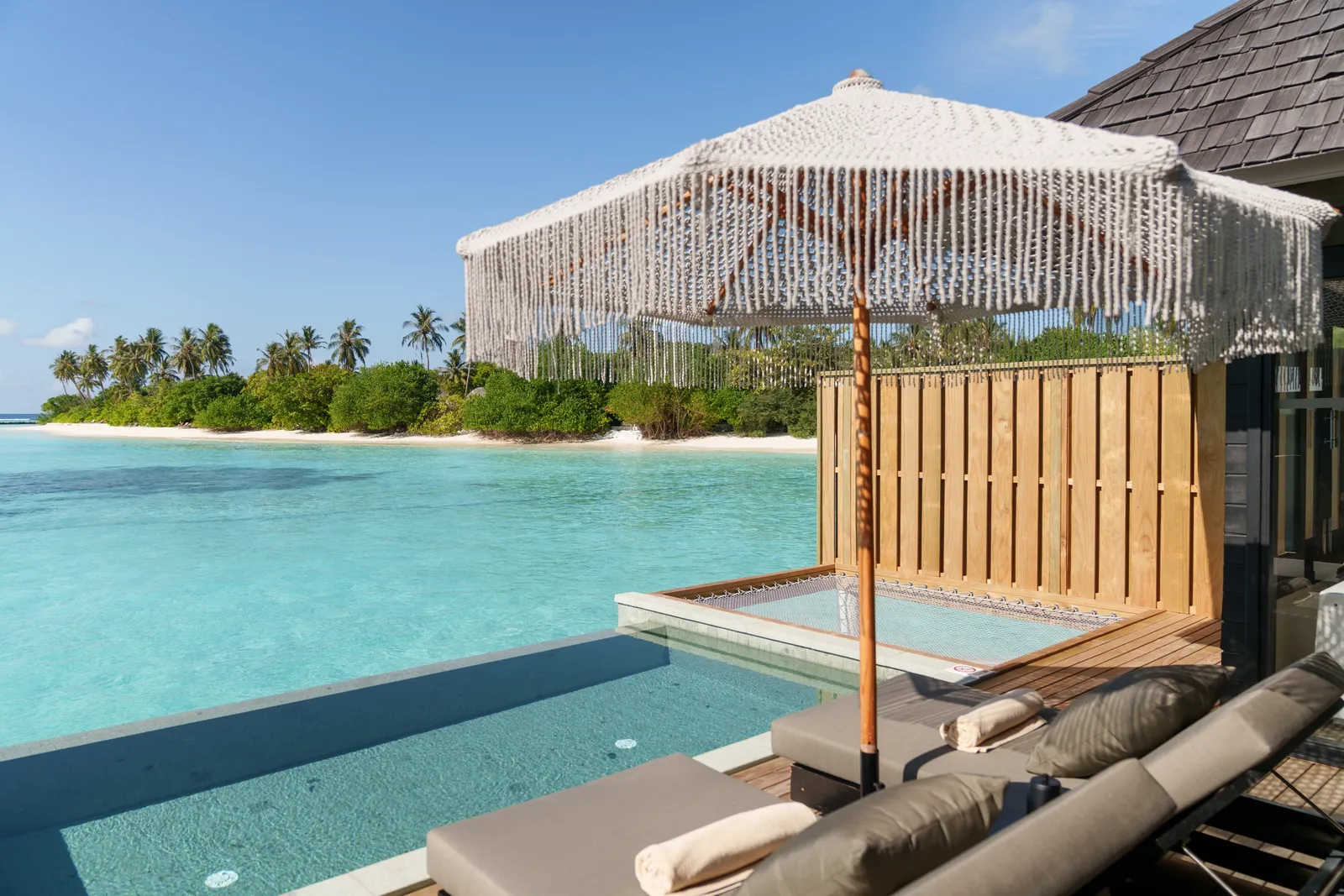 A Water Villa with Pool’s deck: the pool, the parasol and the lagoon out to the island opposite.