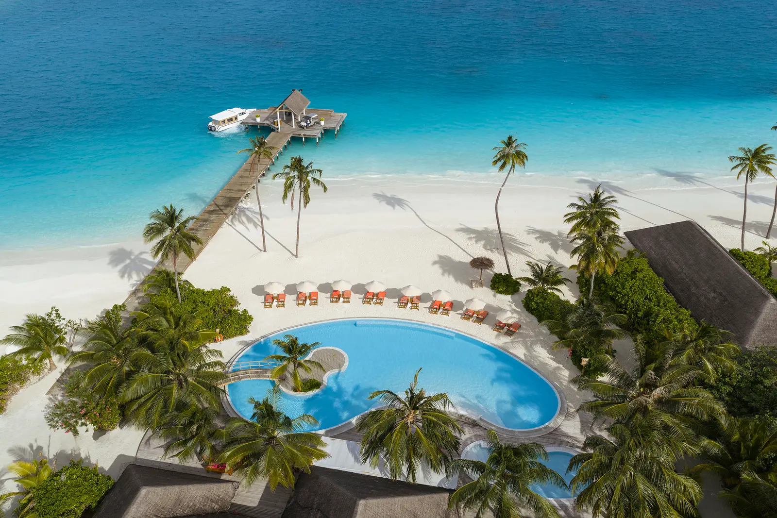 The main pool beside Chemistry Bar from above, with loungers, palms and the jetty on the lagoon.