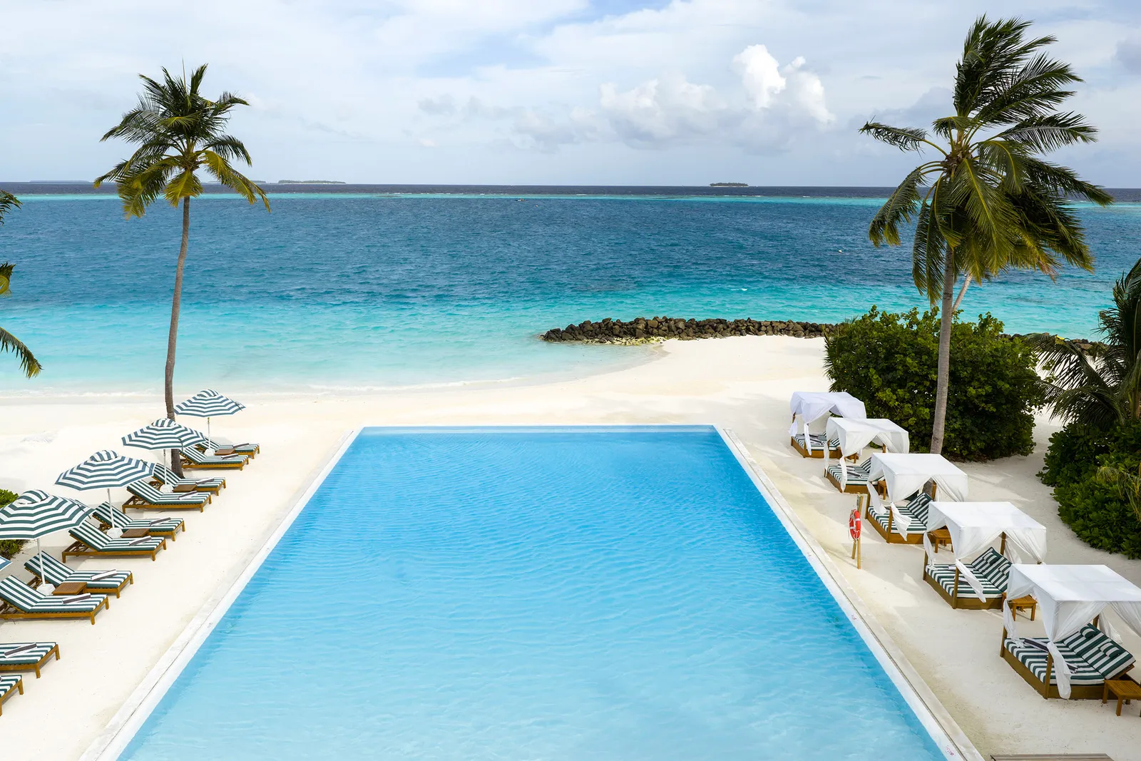 Fresh Water’s adults-only pool on the beach, with striped loungers and cabanas.