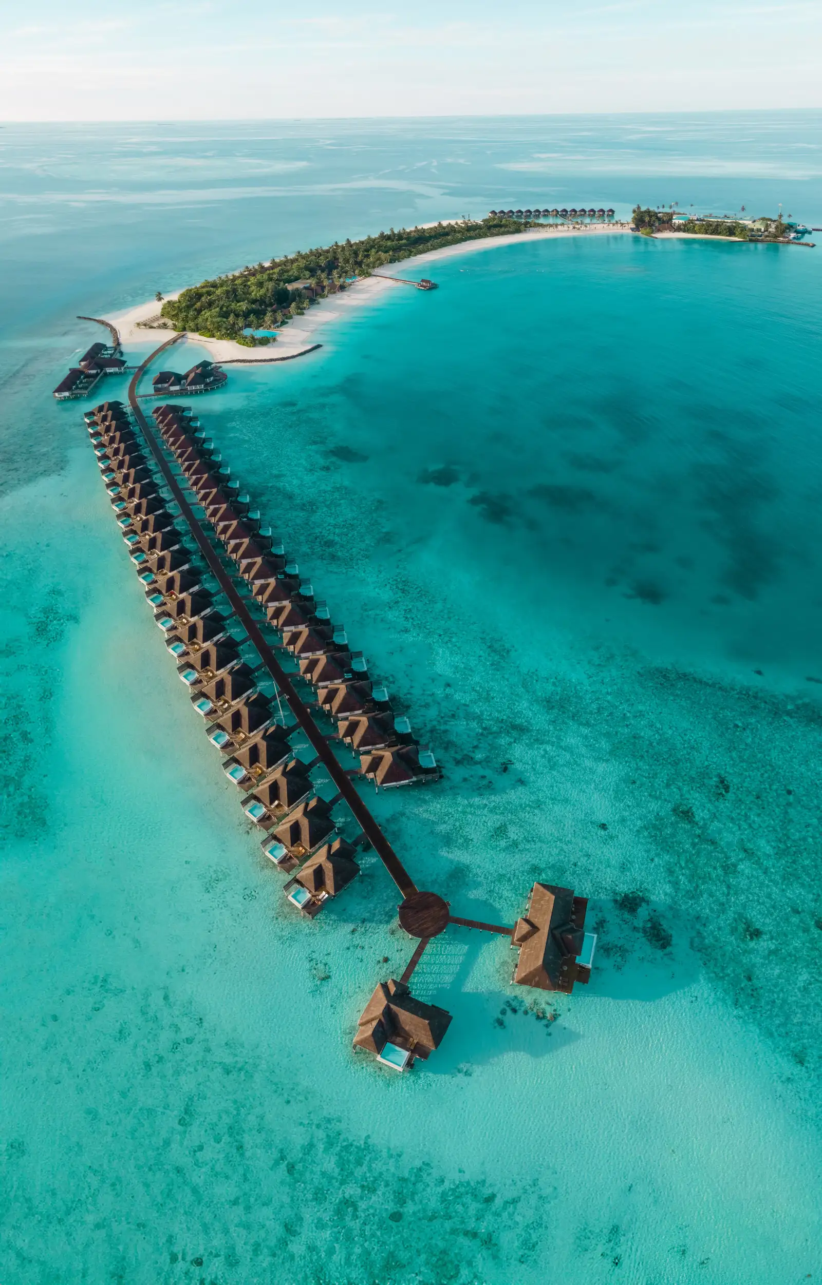 The island from a distance: the crescent of sand, the greenery and the long line of water villas reaching into the lagoon.
