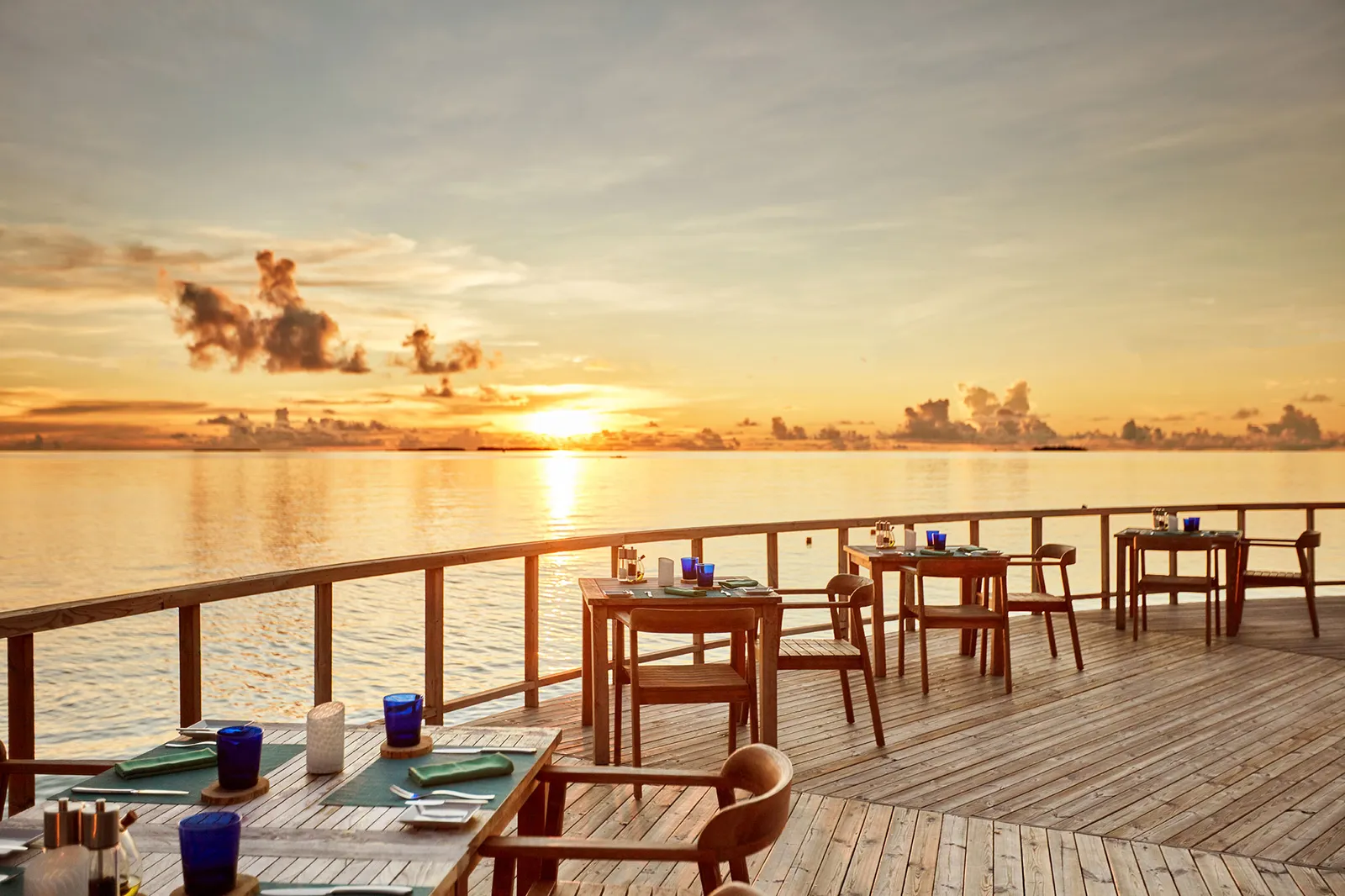 Roma’s terrace over the water at sunset, tables laid and the sun low over the lagoon.