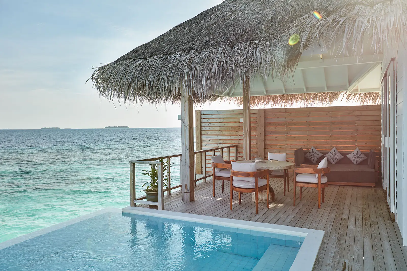 The Ocean Residence with Pool’s veranda, with its dining table, sofa and the pool over the sea.