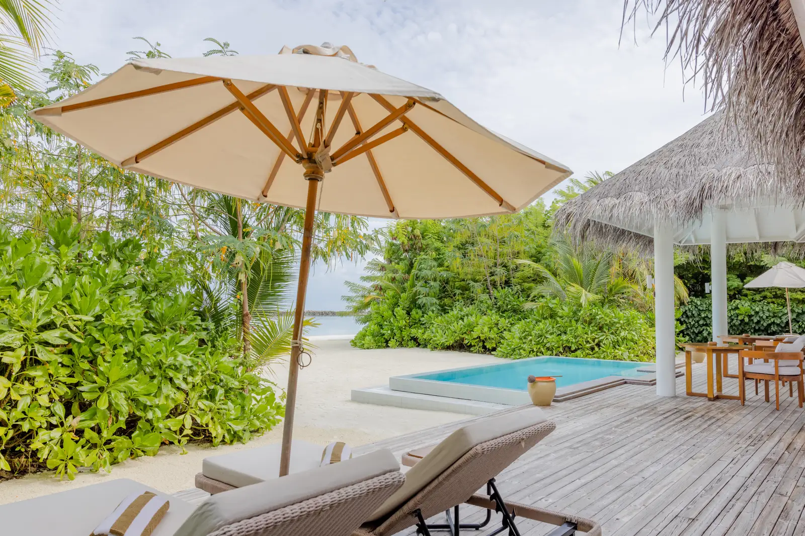 The Two Bedroom Beach Residence with Pool’s deck, with the parasol, loungers and the pool facing the sea.