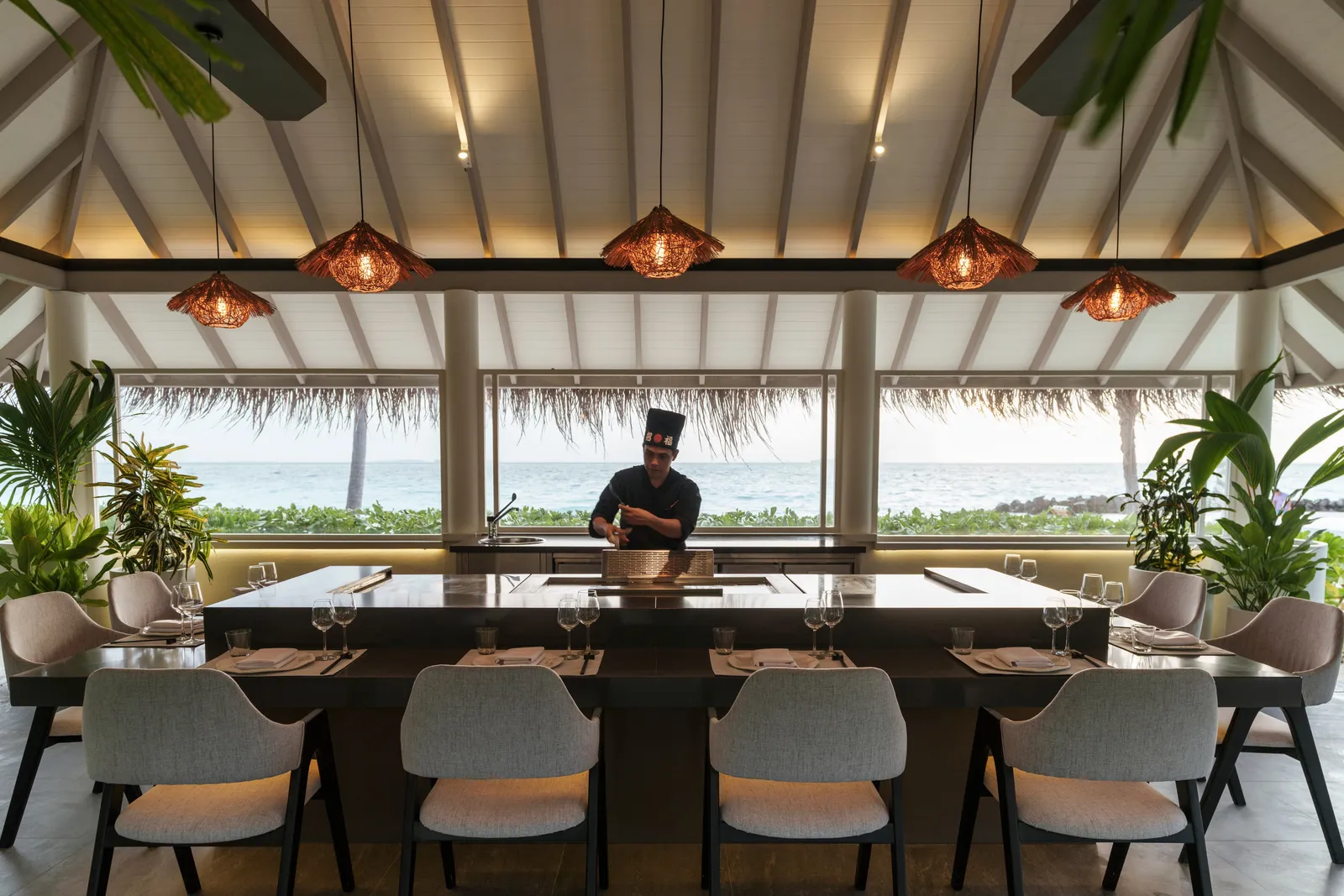 The teppanyaki: the chef at the hotplate facing the 8 counter seats, copper lamps and the lagoon behind.