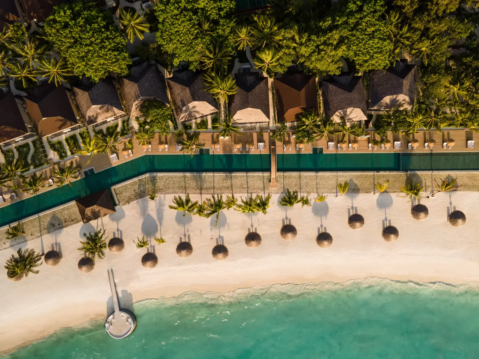 The beach from above, loungers under the palms and the villas behind