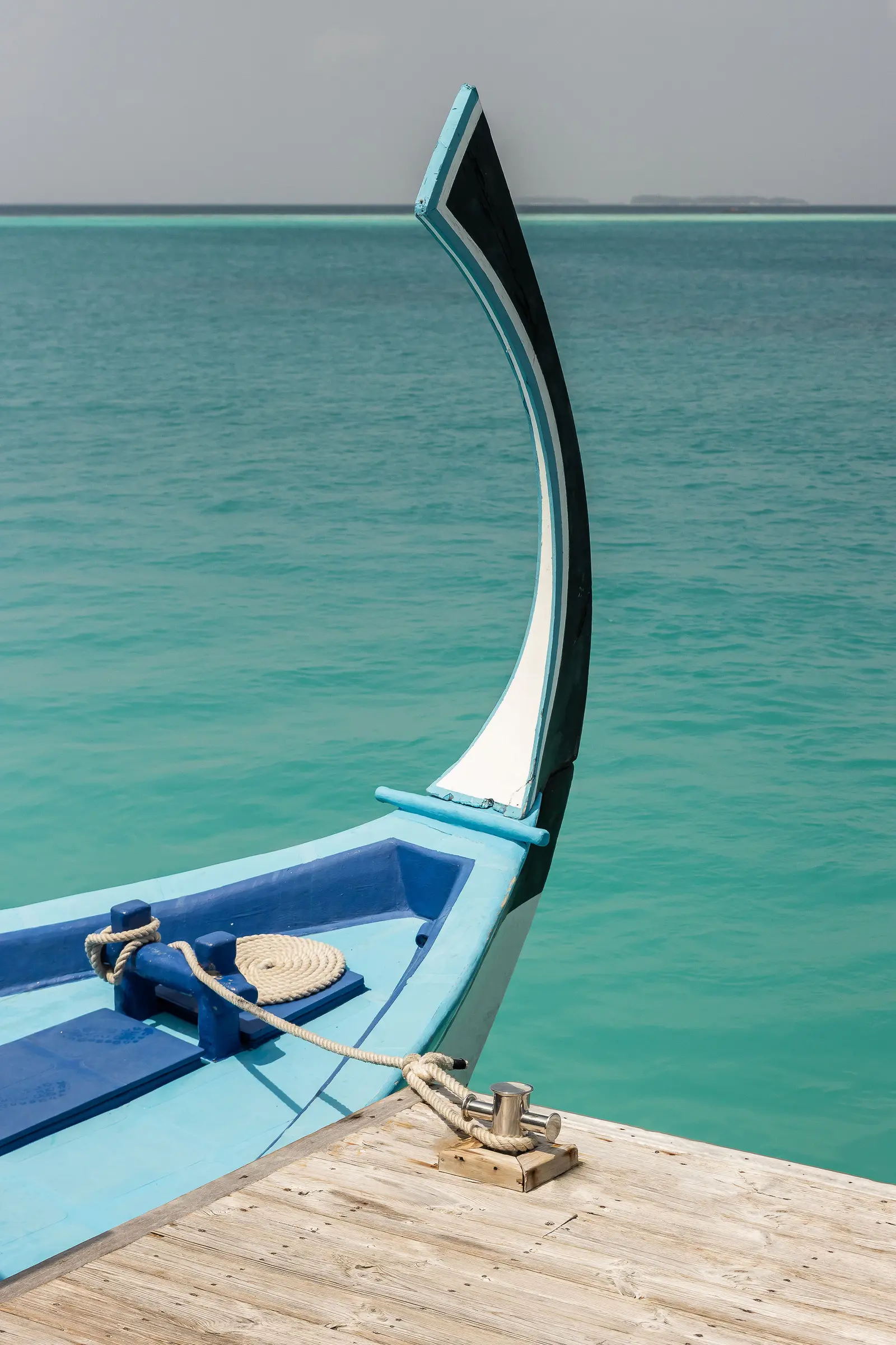 The prow of a dhoni moored at the jetty, on turquoise water