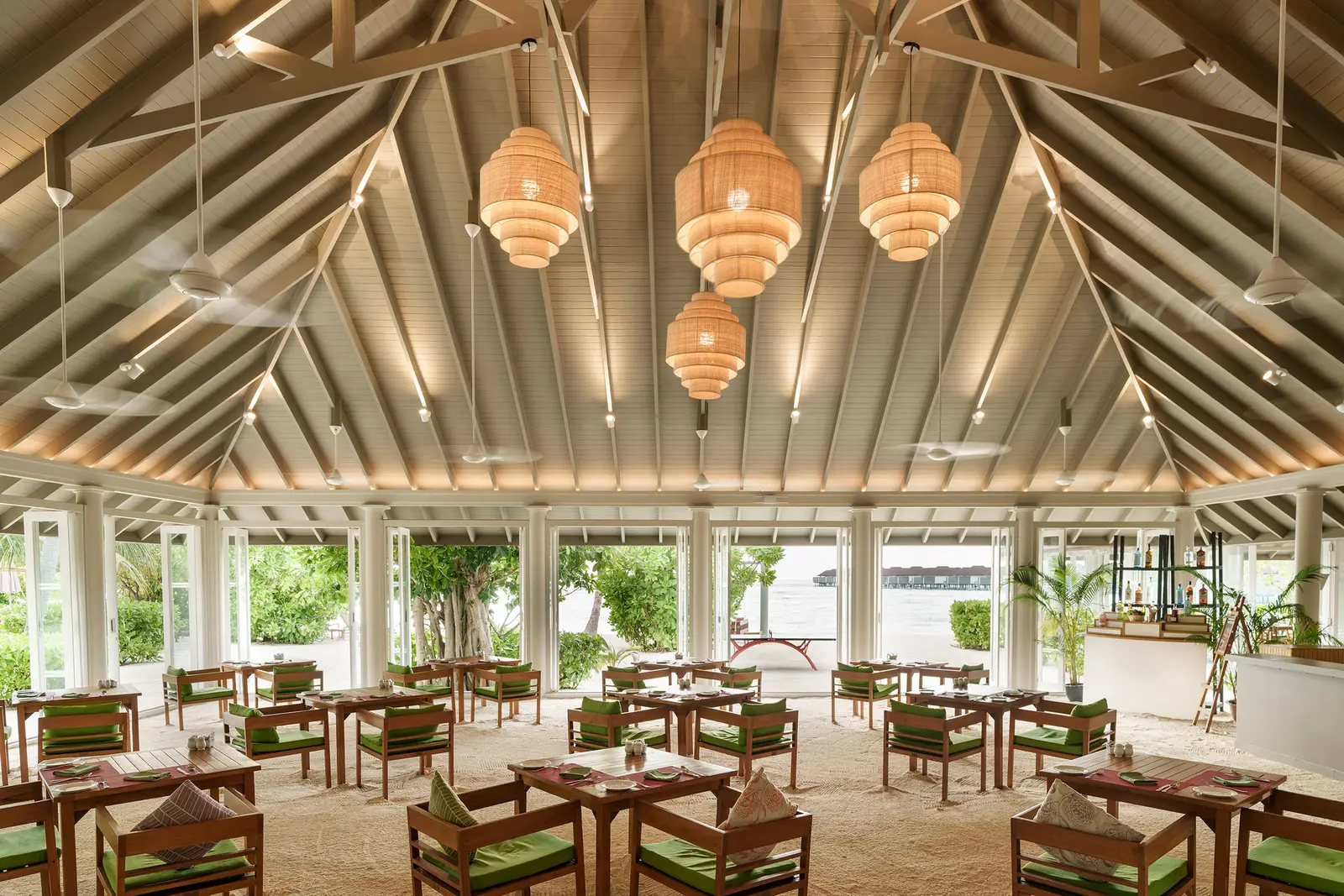 Malaafaiy’s dining room under the timber roof, with wicker lamps