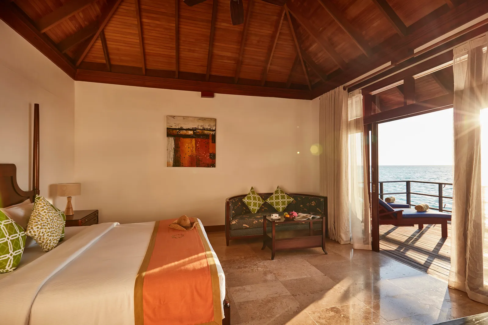 A Deluxe Water Villa bedroom, the bed and sitting area in the sea light