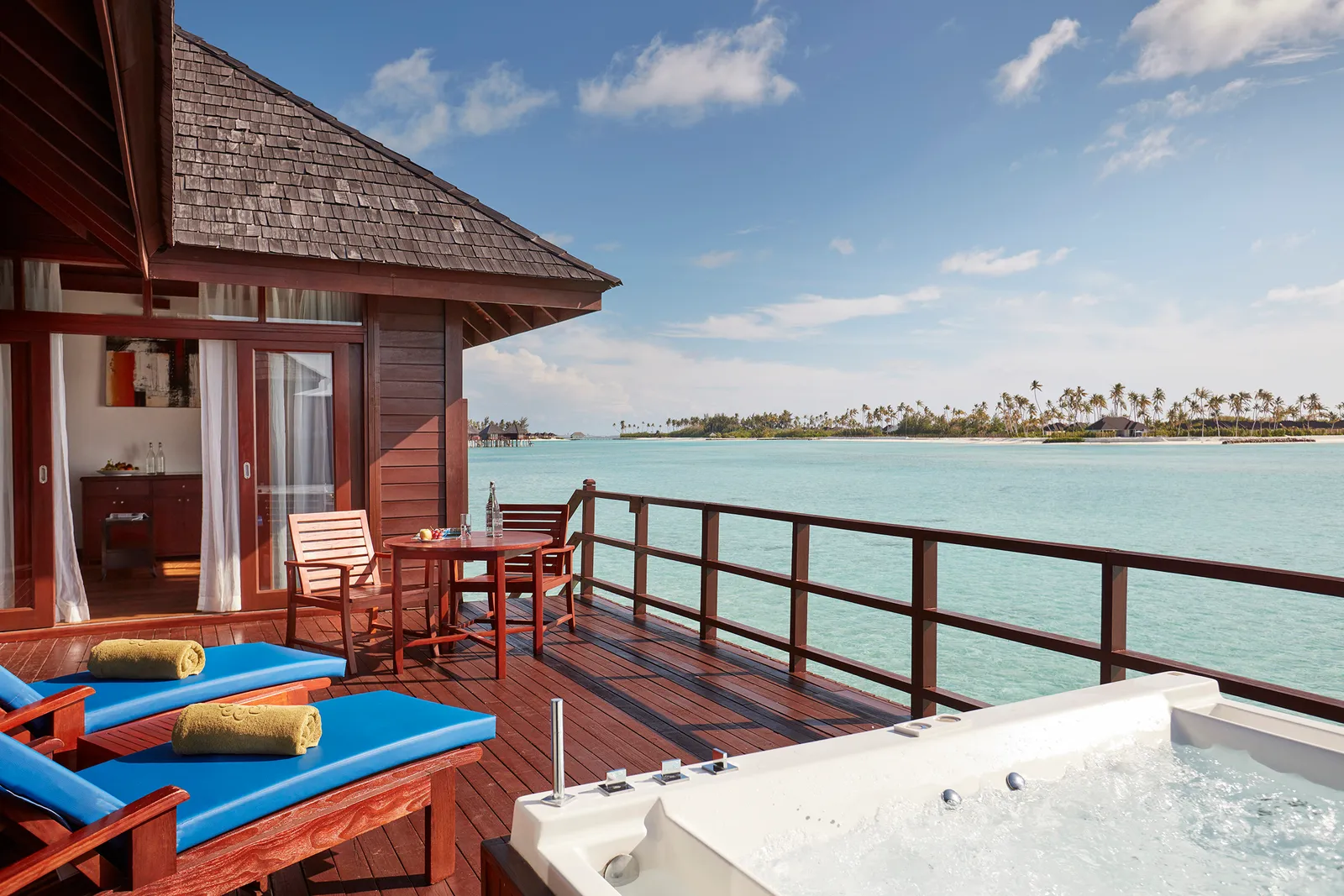 The Prestige Jacuzzi Water Villa deck, its hot tub and loungers over the lagoon