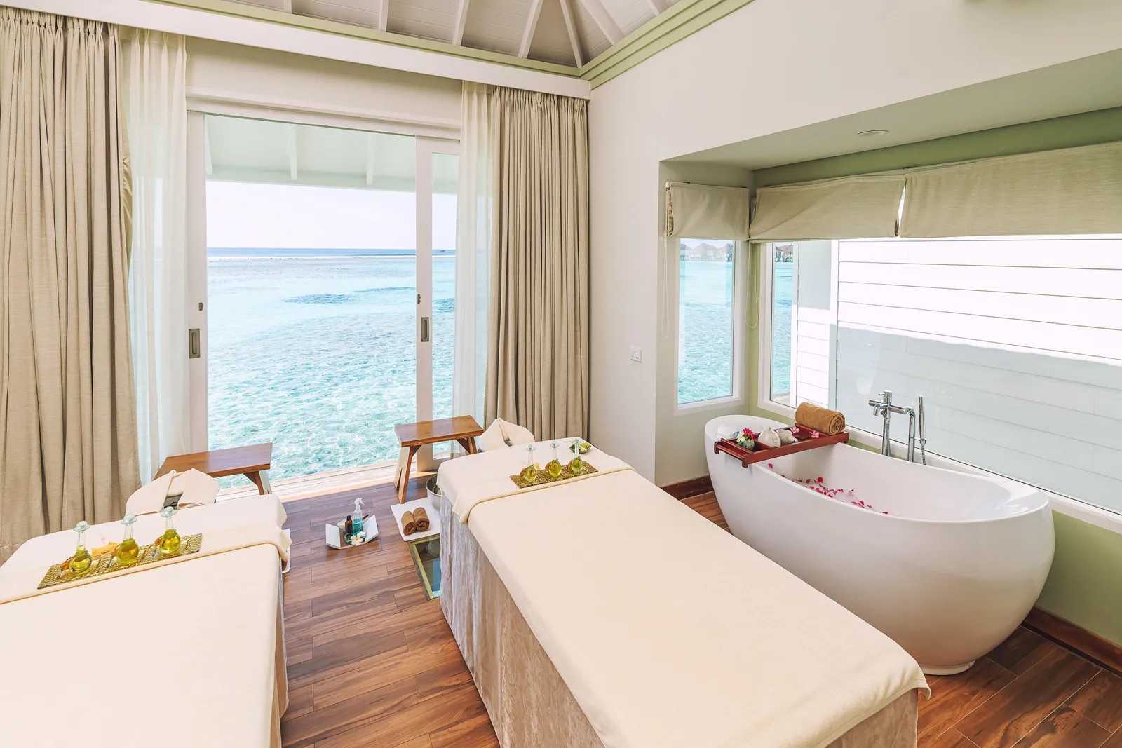 A spa room with 2 beds and a petal-strewn bath, facing the sea