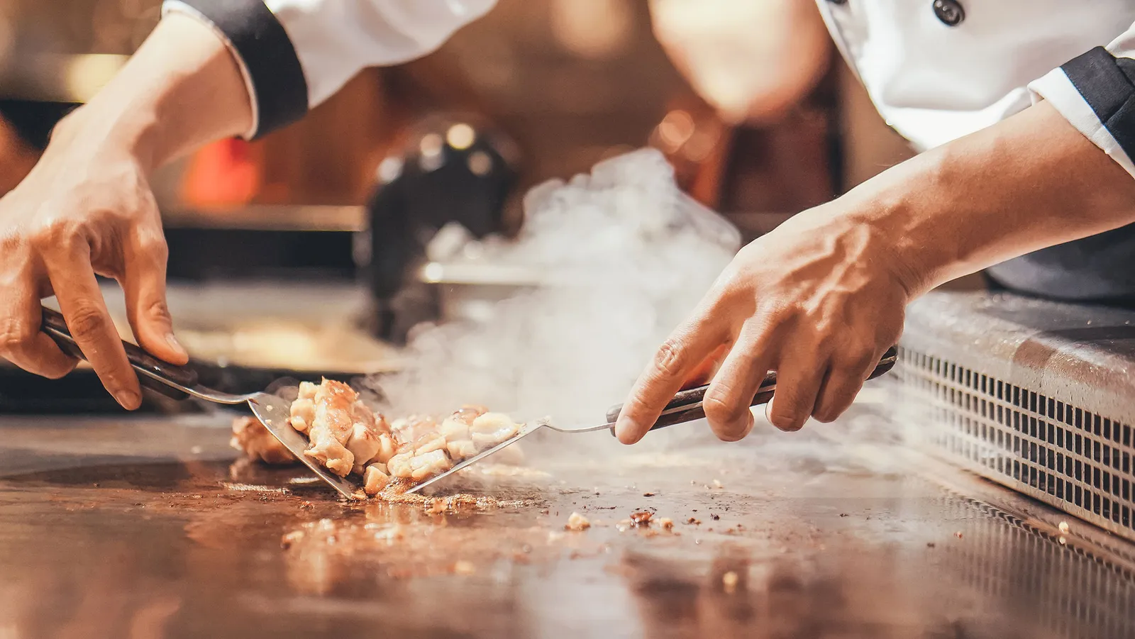 The chef at the teppanyaki grill, steam rising off the plate