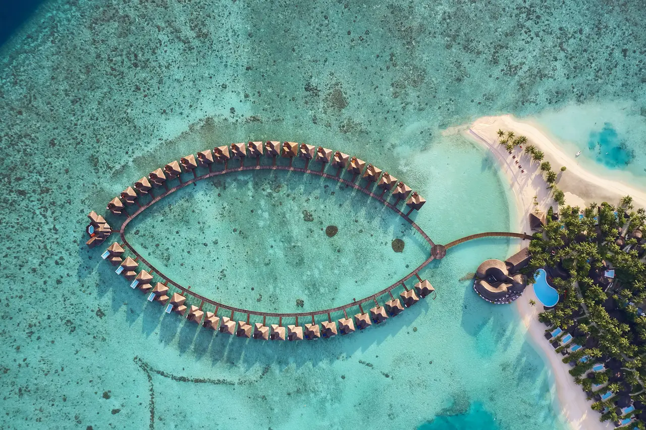 The water villas from above, laid out in the shape of a leaf over the lagoon, with the jetty tying them to the island.