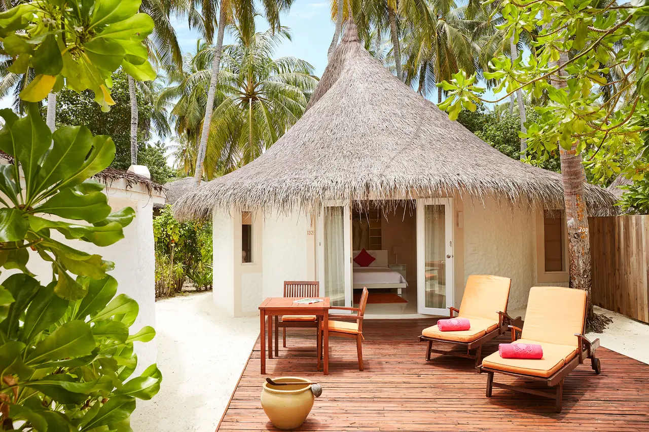 A Beach Villa with Pool under its thatched roof, with loungers on the timber veranda and palms around it.