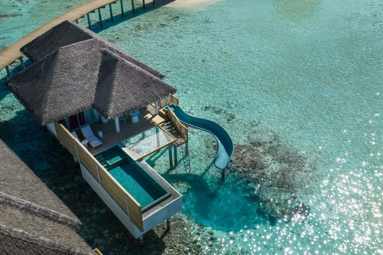 An Ocean Signature Villa from above: the thatched roof, the pool on the deck and the slide running down into the lagoon.
