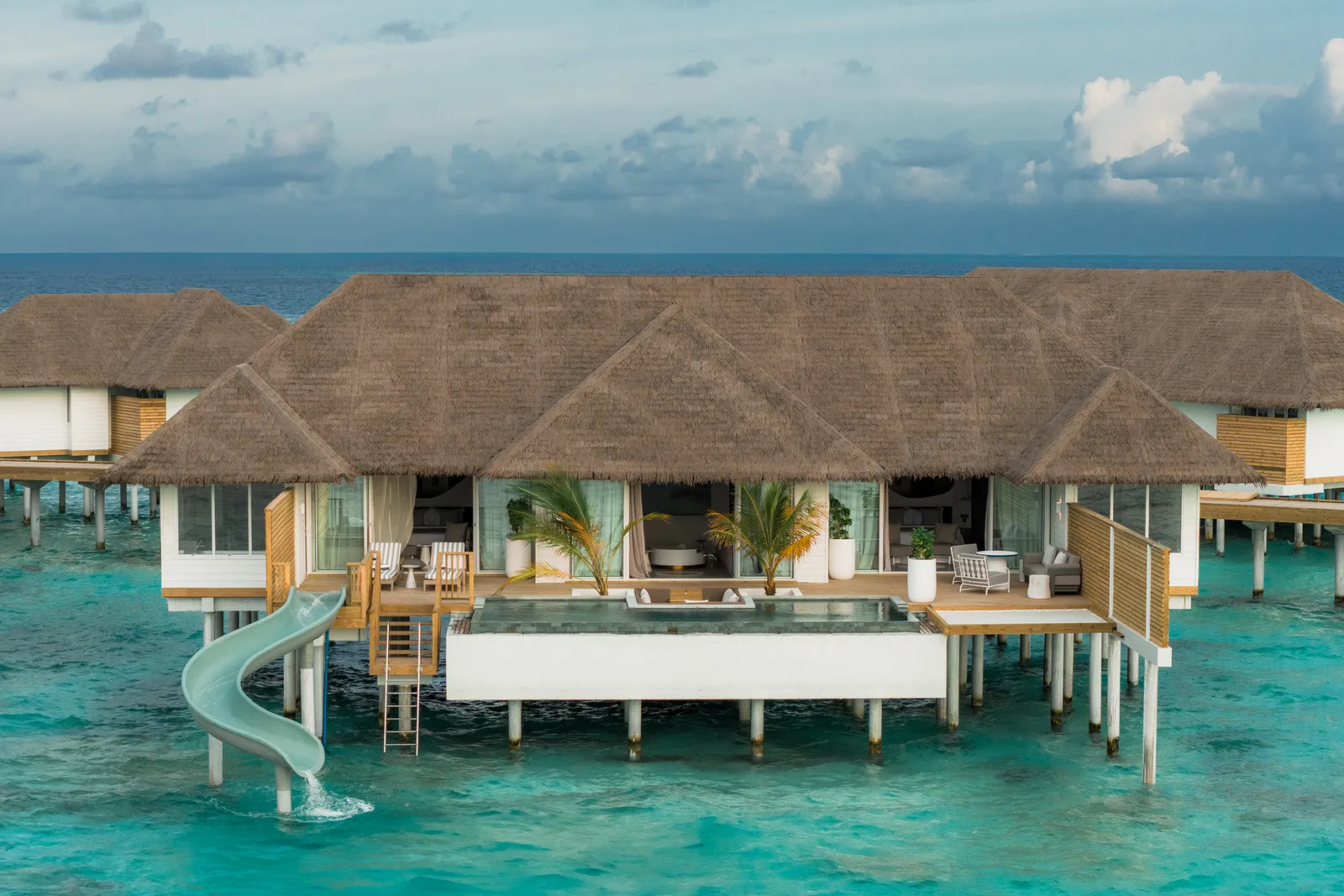 The Two Bedroom Ocean Signature Villa from the sea: the broad thatched roof, the pool and the slide to the water.
