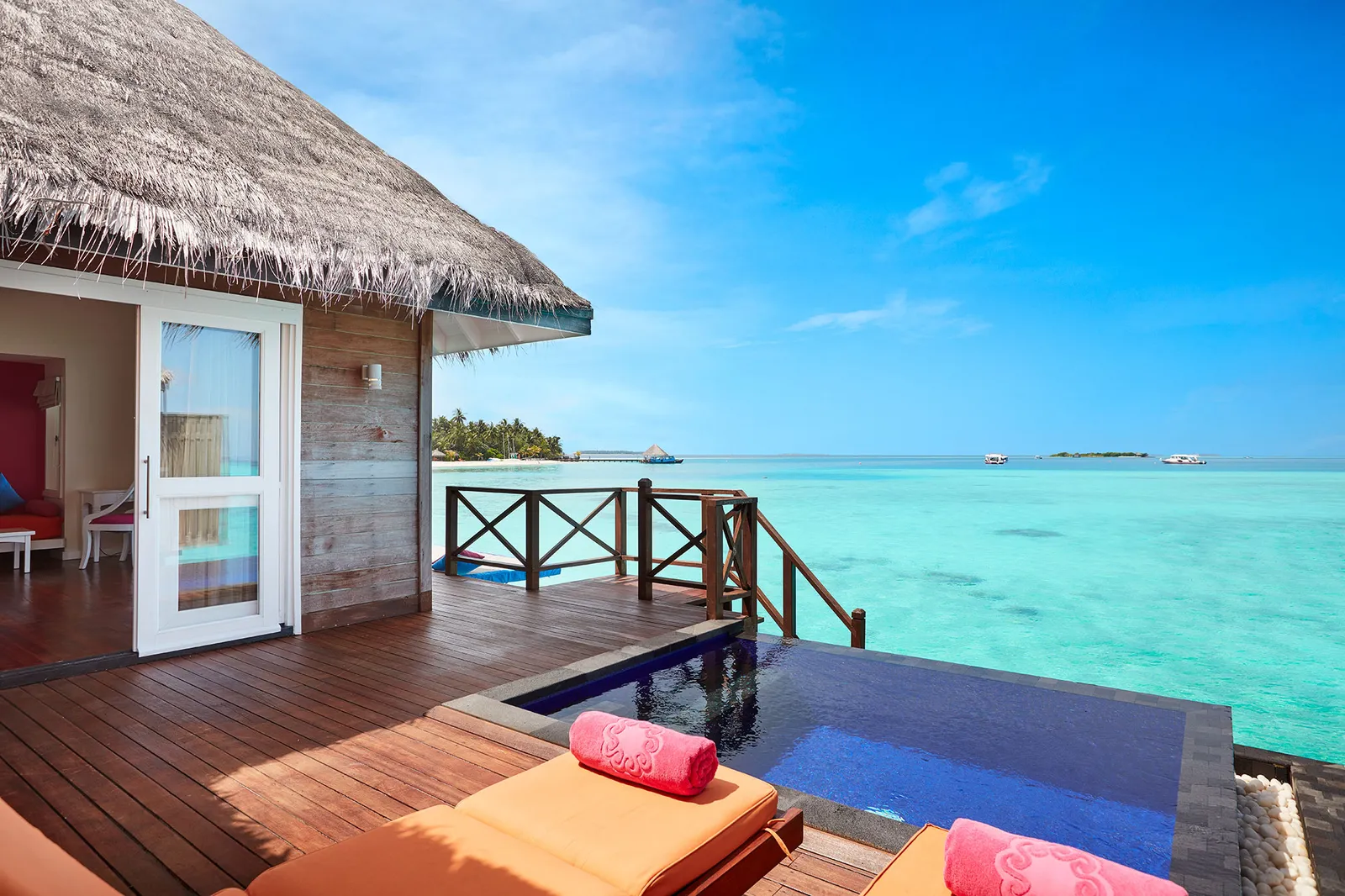 The infinity plunge pool on a Water Villa with Pool’s deck, with loungers and the turquoise sea ahead.
