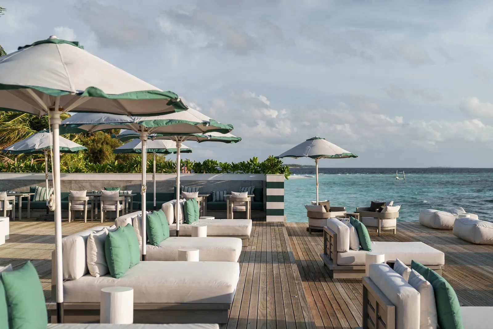 The Nautilus deck over the water: white sofas, green cushions and pale parasols facing the sea.