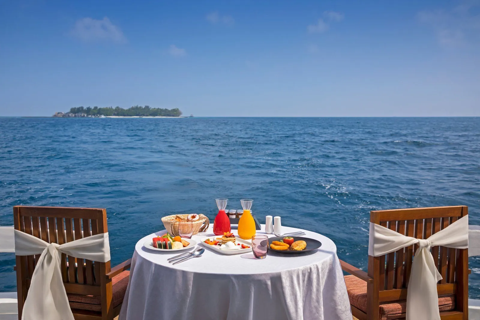 Breakfast laid on board the dhoni, with the open sea and an island on the horizon.