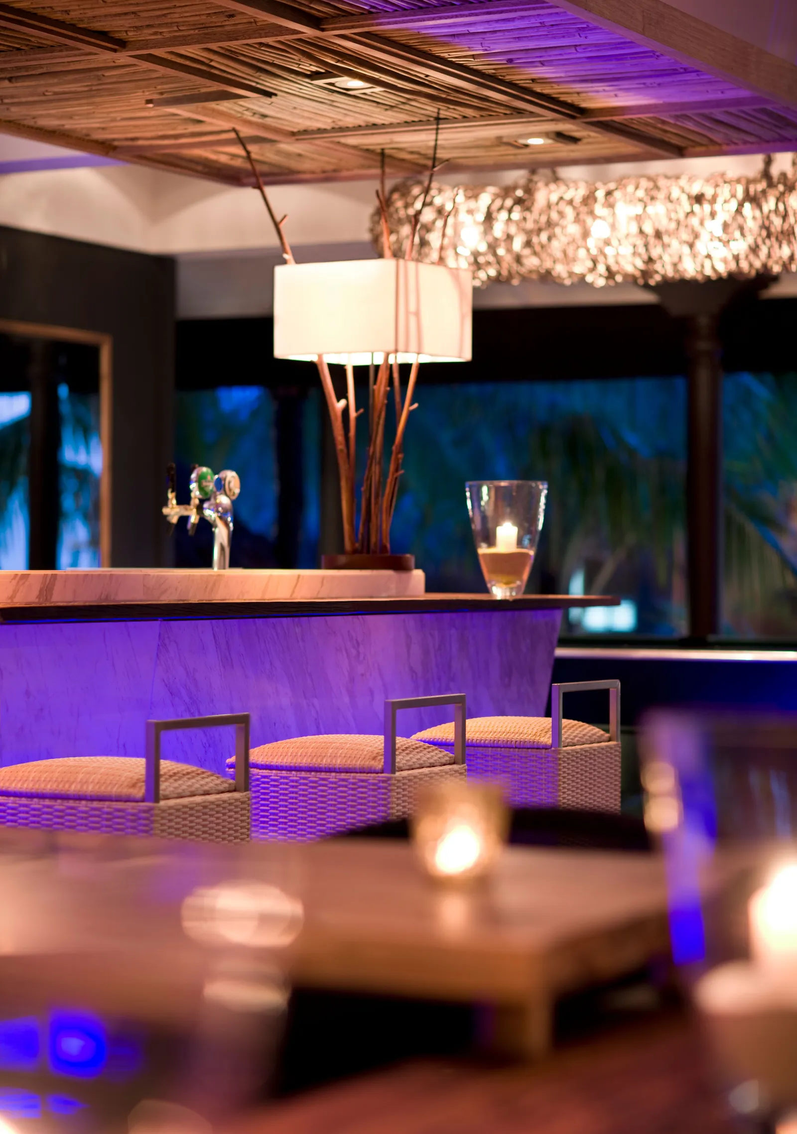 The bar at night, candles lit on the low tables and the counter glowing violet.