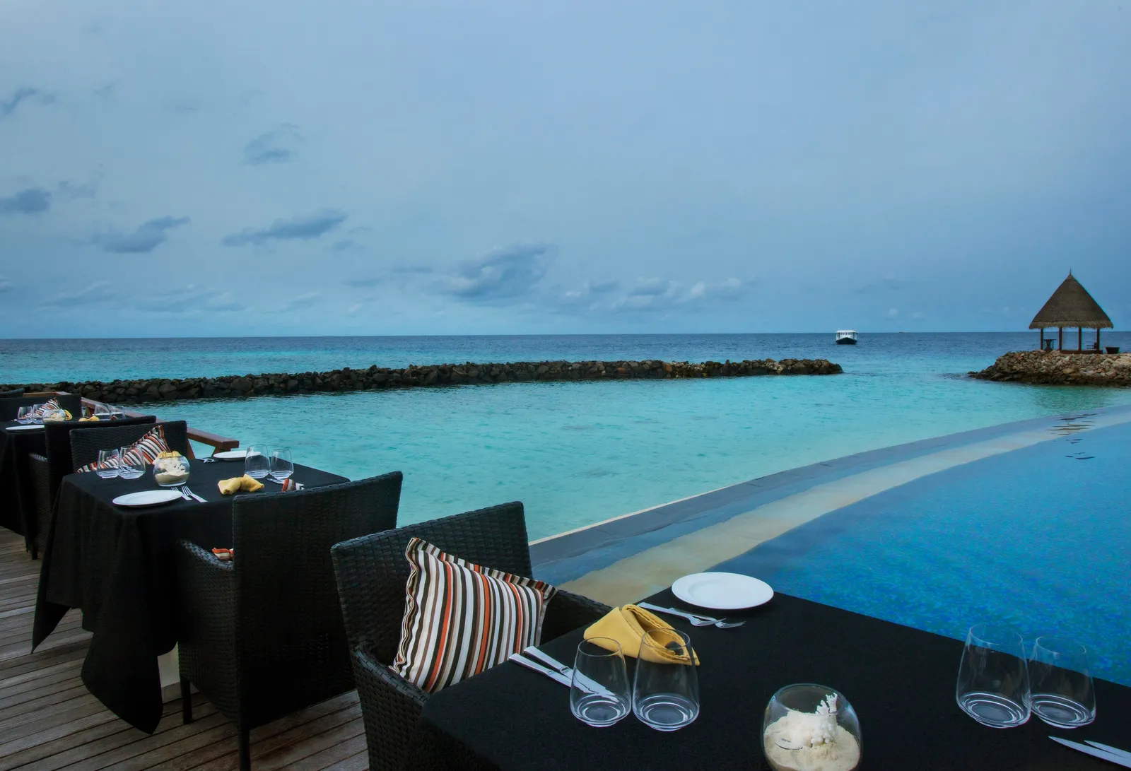 Open The Grill’s tables on the edge of the pool, with the lagoon and the gazebo on the breakwater beyond.