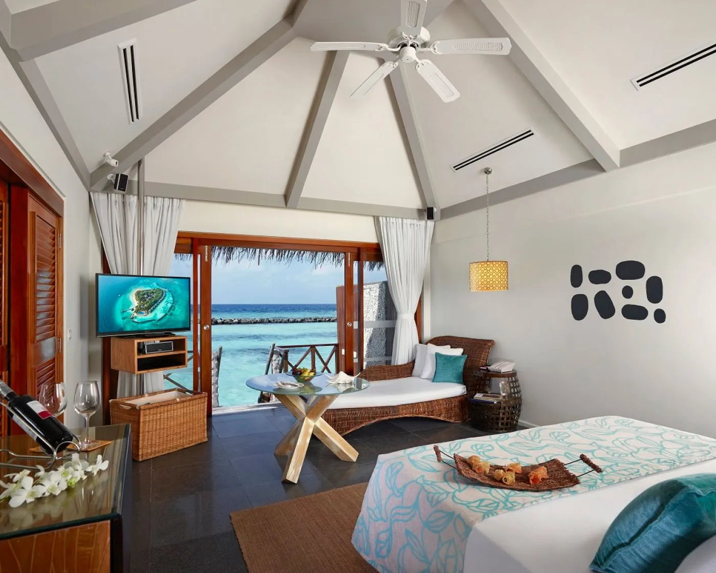 A Premium Water Villa bedroom, with its peaked ceiling and glass doors onto the deck and the lagoon.