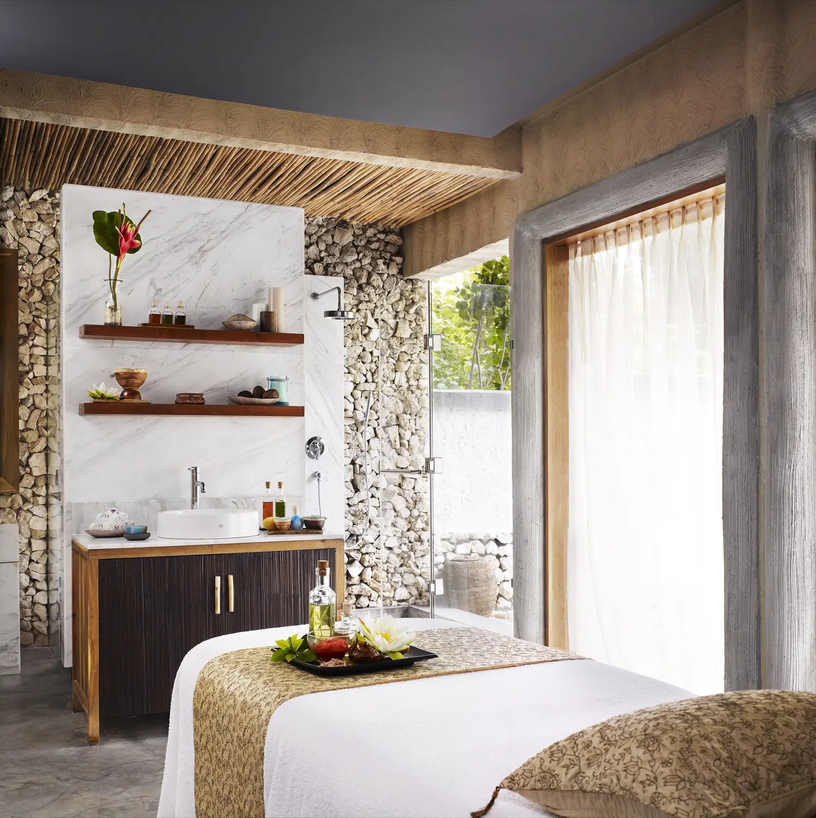 A J Wellness Circle treatment room: the massage bed, the stone basin and curtains open to the light.