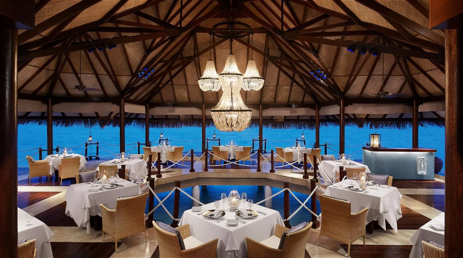 The dining room beneath its timber roof, lit in the evening