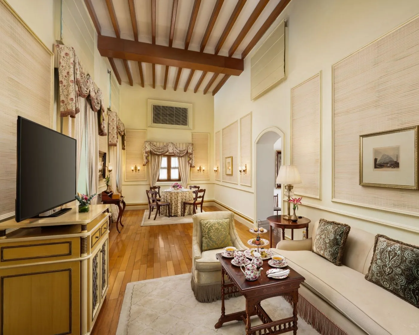 Il soggiorno di una Grand Royal Suite con divano chiaro, televisore e tavolo da tè