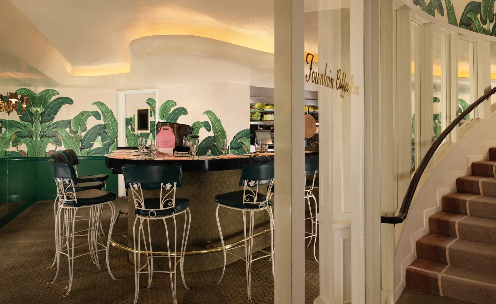 The curved counter of the Fountain Coffee Room with its stools and banana leaves on the walls