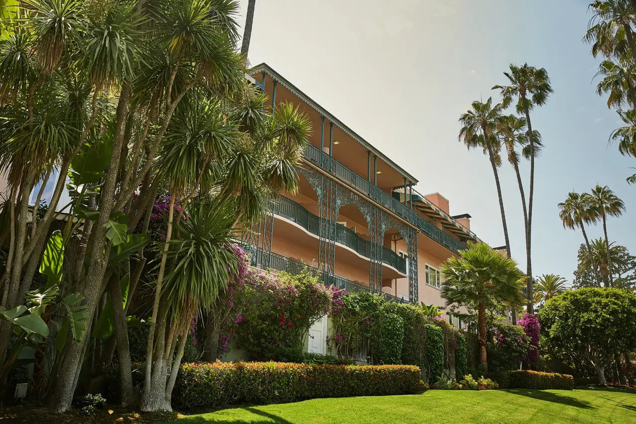 A wing of the hotel with green balconies among palms and garden