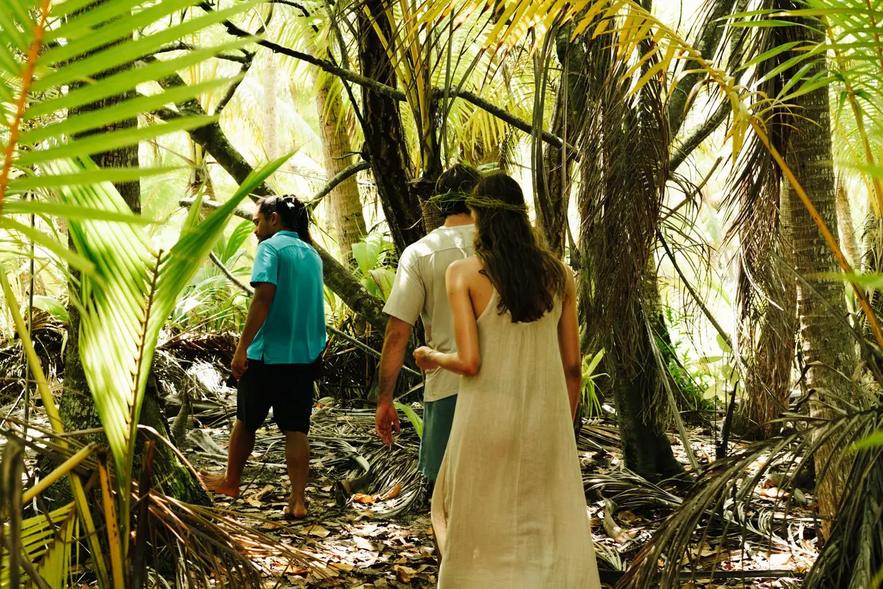 A naturalist guide leads 2 guests through the atoll’s forest