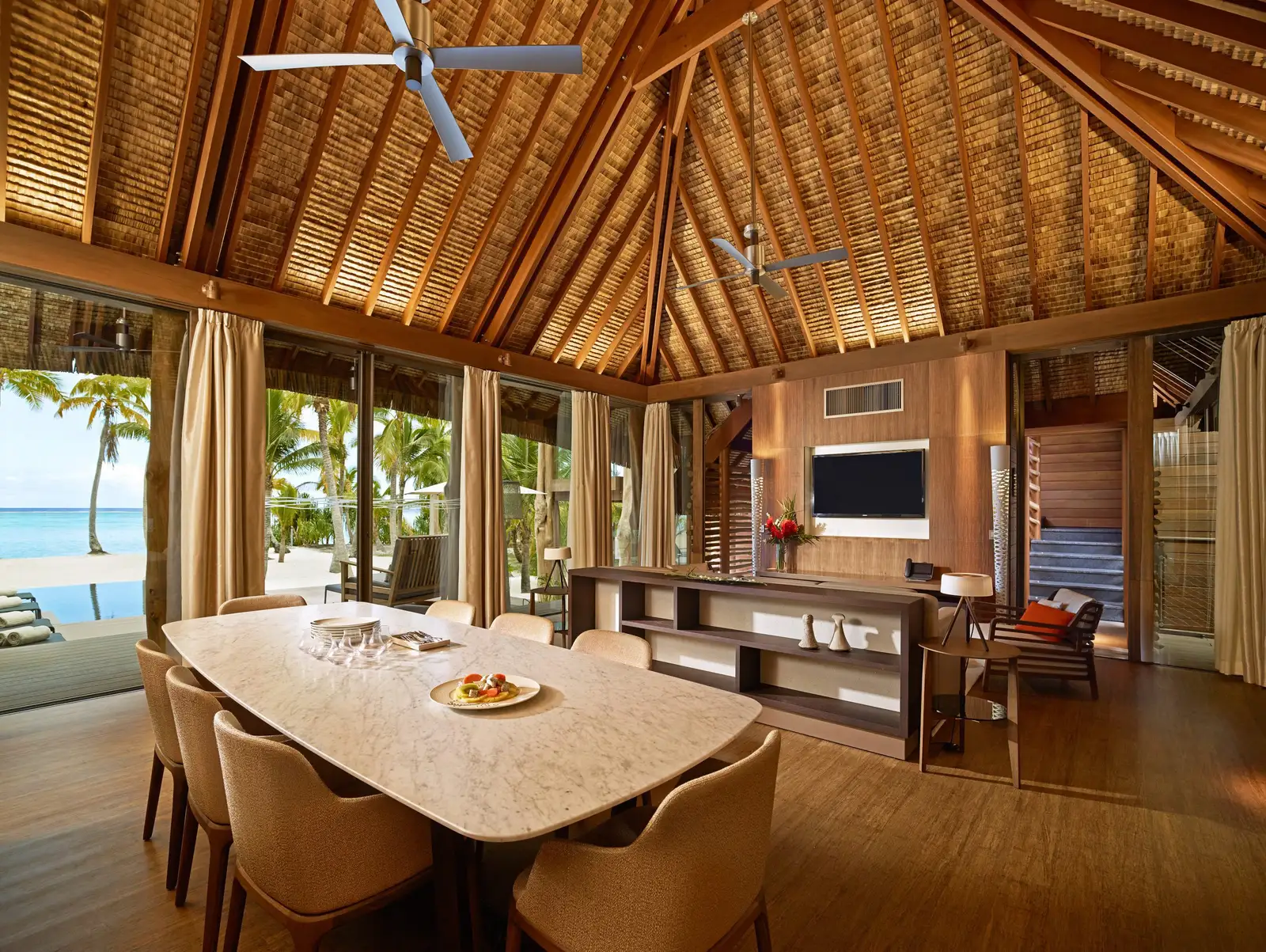 The 3-bedroom villa’s living room: a timber ceiling, a table for 8 and windows onto the garden