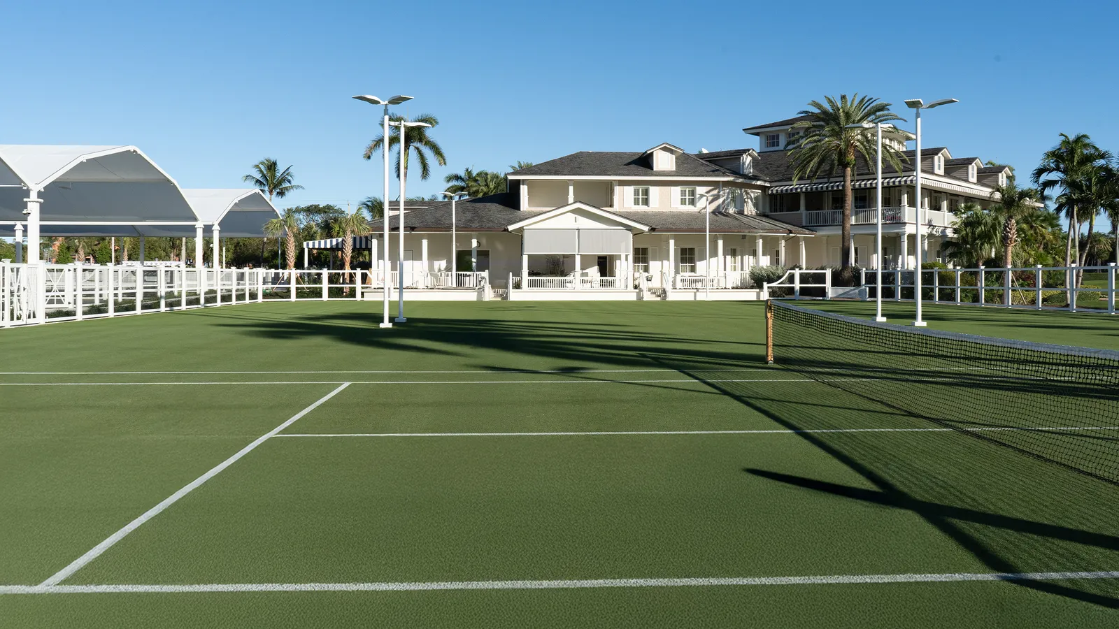The grass tennis courts with the white Golf & Racquet Club house behind.