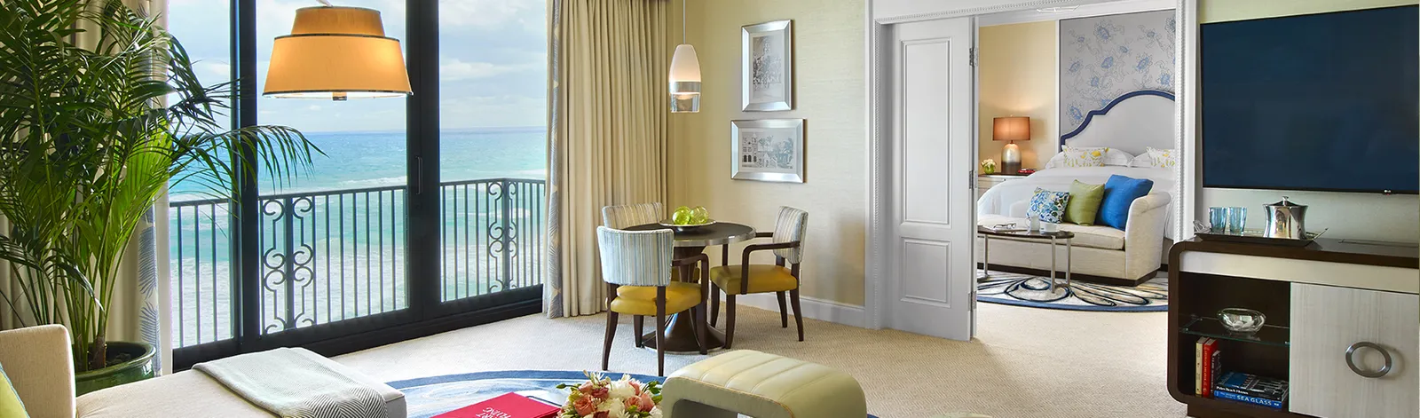A Premium Atlantic Suite: the round table before the glass door onto the ocean and, through the doorway, the bedroom.
