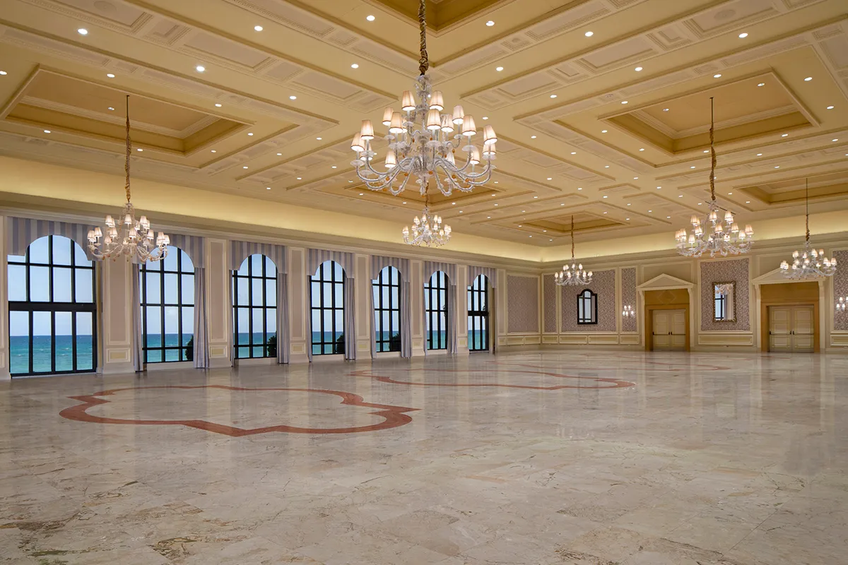 The Venetian Ballroom, empty: marble floor, crystal chandeliers and a row of arched windows onto the ocean.