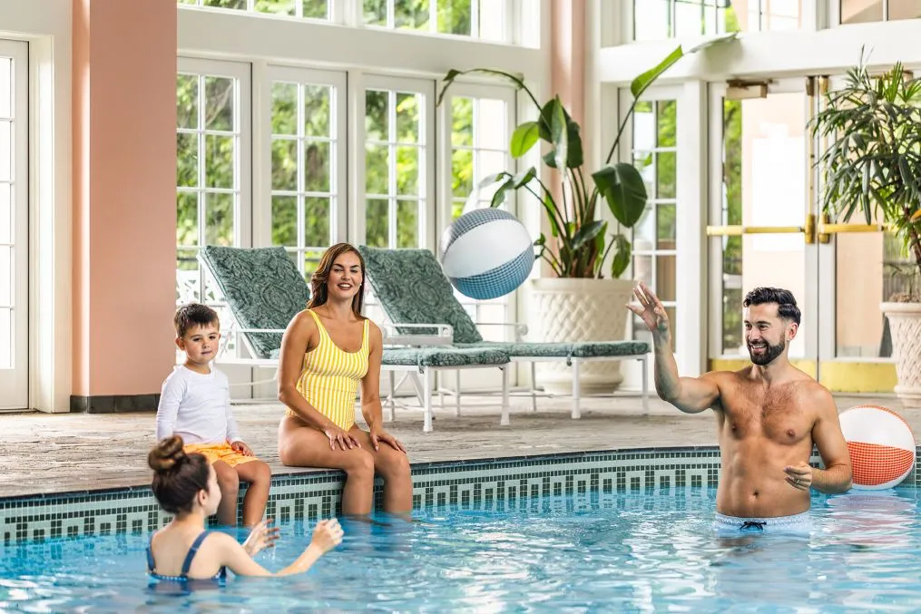A family in the Broadmoor’s indoor pool, with a ball and windows onto the grounds