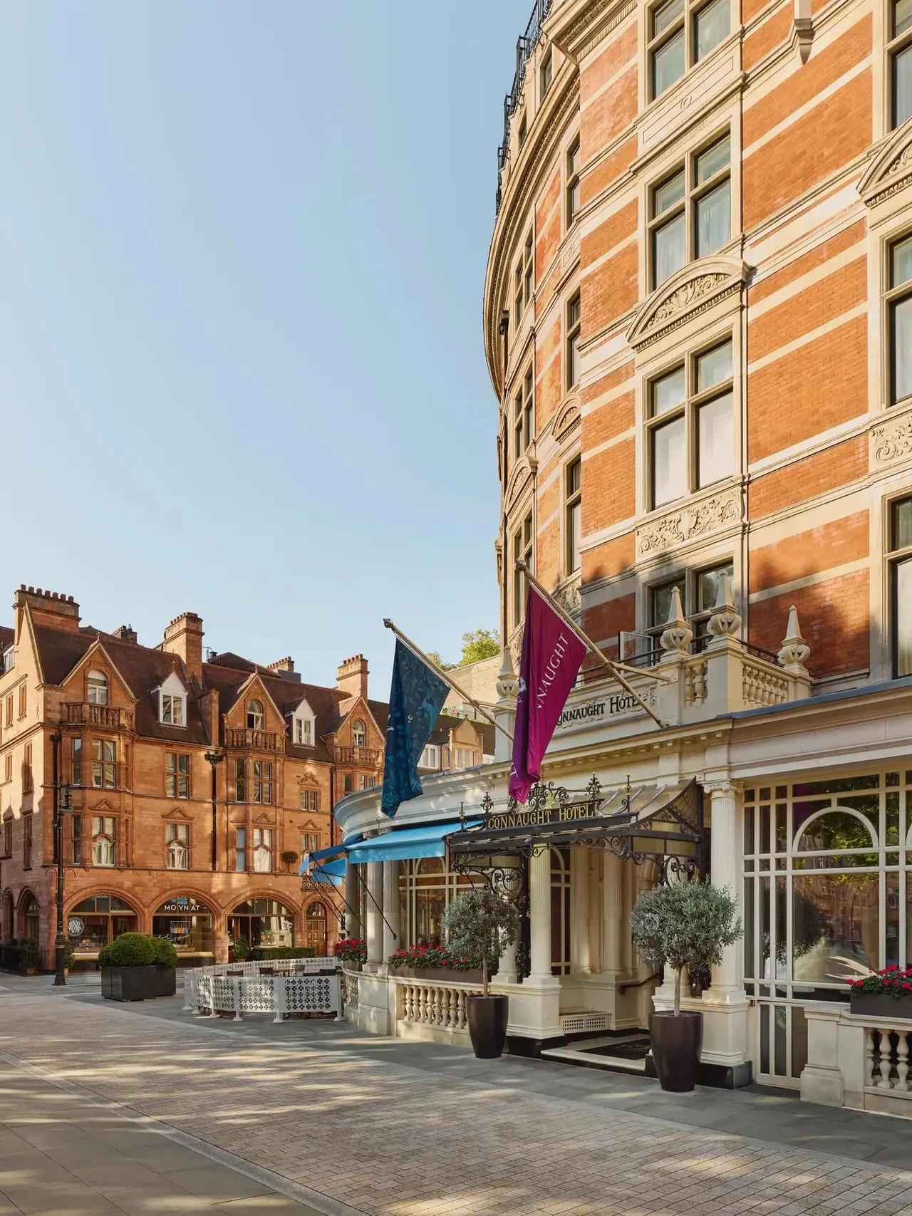 The Connaught’s red-brick façade curving round Carlos Place, with flags above the entrance