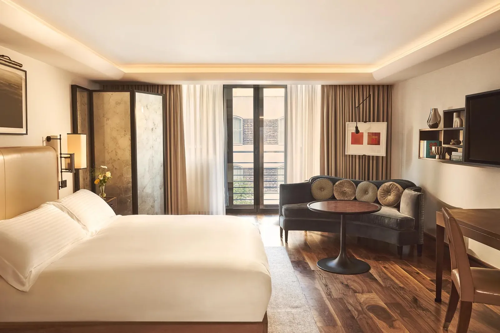 A Contemporary Studio: bed and a sitting corner with a round table in one space, parquet and French windows