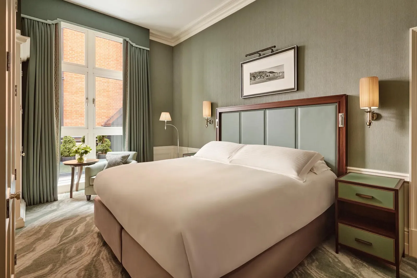 A Courtyard Superior Room: a white bed, a duck-egg upholstered headboard and windows onto the courtyard