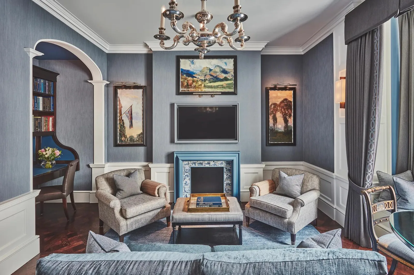 The Grosvenor Suite: a blue sitting room with a tiled fireplace, a silver chandelier and shelves in an arch