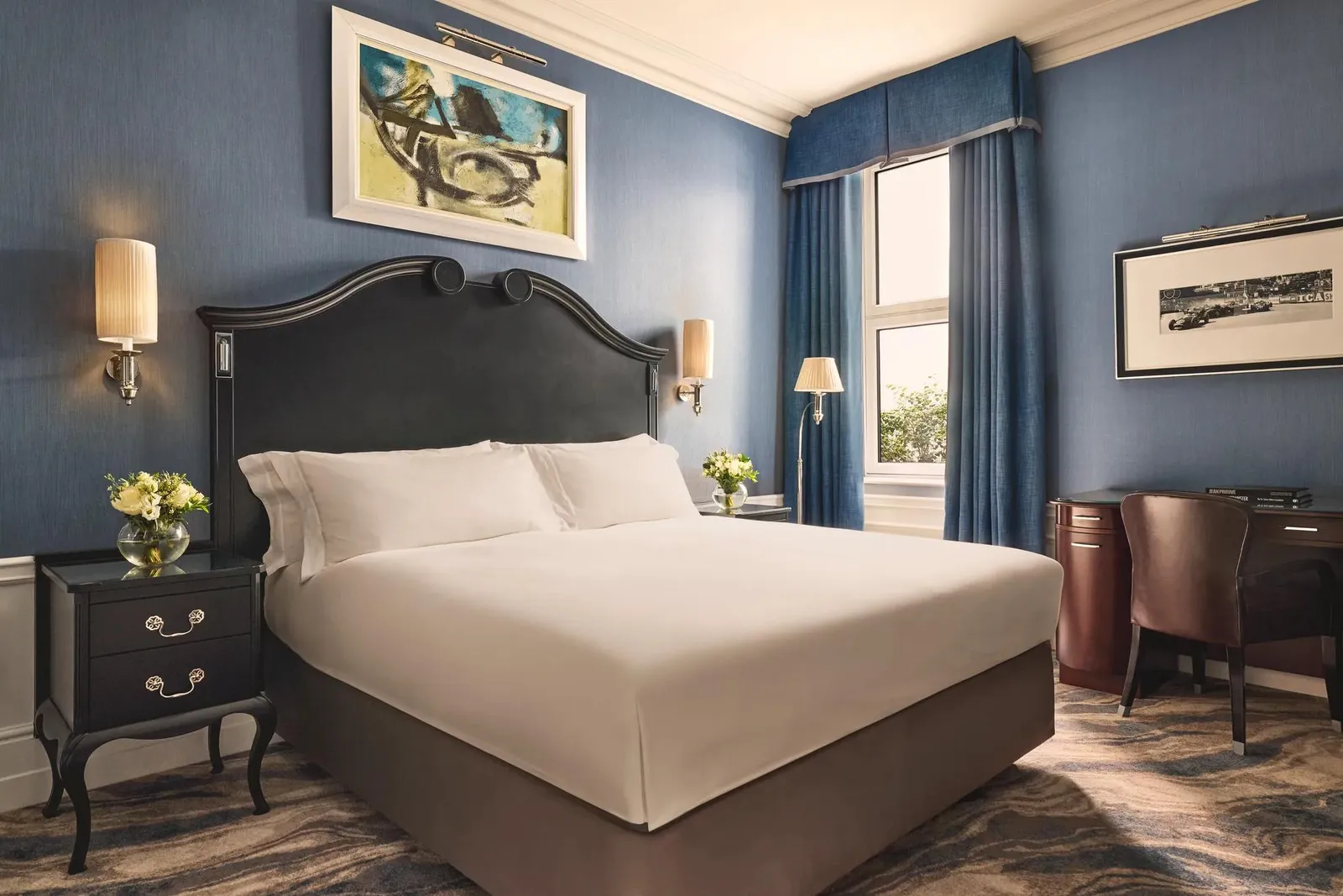 A Superior Room: a king bed with a dark headboard, blue walls and an abstract painting above the bed