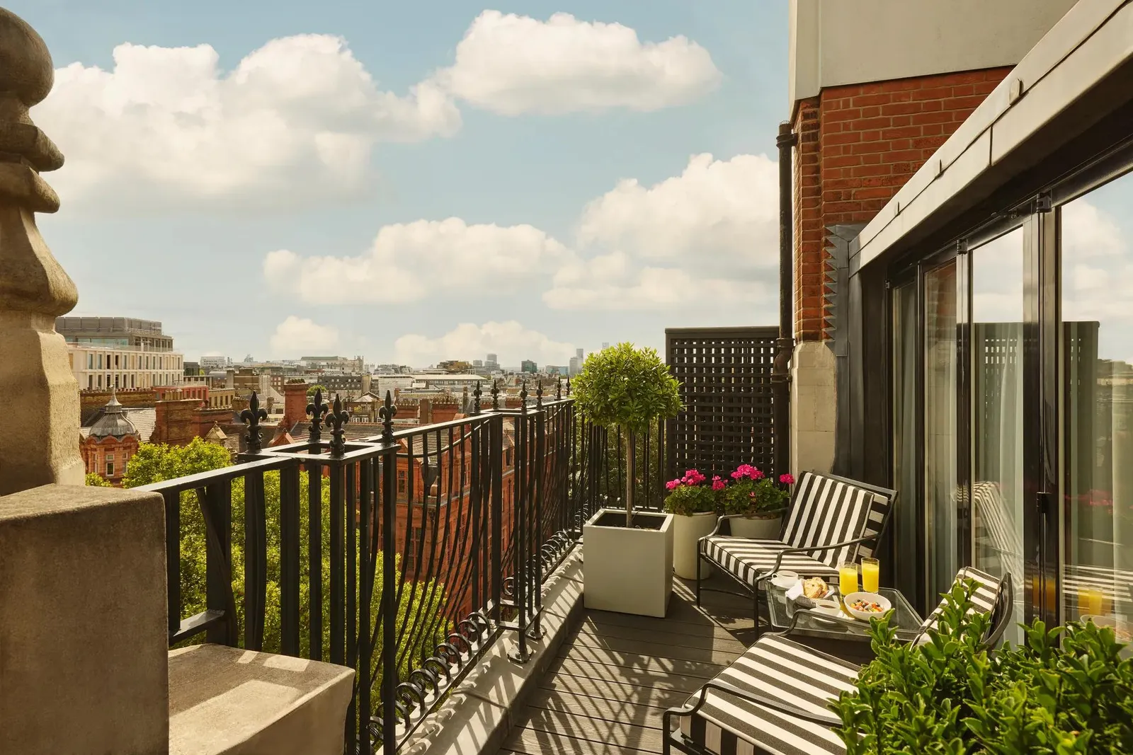 The Apartment’s balcony: striped loungers and flowerpots above the trees of Carlos Place